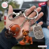 Closeup of Cleveland Browns 80th Anniversary Metal Keychain with helmet, bulldog figurine, and tag in hand.