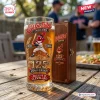 Front view of a beer glass featuring Chief Wahoo graphics and 125th anniversary text, sitting on a wooden table.