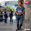 Front view of a man wearing a blue Dallas Cowboys distressed t-shirt with frayed edges at a football stadium.