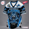 Front view of a Detroit Lions mascot t-shirt featuring a lion graphic, city skyline, and football team branding.