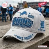 Side view of a white distressed baseball cap featuring blue team logos and the text One Pride on a wooden table.