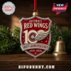 Detroit Red Wings 100th Anniversary 2026 Advent Calendar ornament featuring a red and silver shield design on wood table.