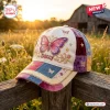 Front view of the Dolly Butterfly Patchwork Baseball Cap resting on a wooden fence outdoors at sunset.