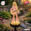 Front view of a Dolly Parton Limited Edition Solar Garden Light featuring a glowing pink figure playing a guitar.