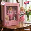 Front view of a blonde country singer collector doll holding a guitar next to its pink packaging box.