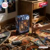 Close-up of a hand holding an E.T. 45th Anniversary Hot Toys figure next to its original retail box on a patterned rug.