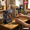 Close-up of hands holding an E.T. 45th Anniversary Hot Toys figure beside its illustrated product box on a wooden desk.