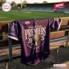 Front view of the Fremantle Dockers AFL 2026 Champions Baseball Jersey draped over a wooden stadium bench.