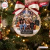 Close-up of a clear spherical Christmas ornament featuring a group on a sofa with a fountain background.