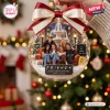Front view of a clear spherical Christmas ornament featuring a group on an orange sofa and a holiday fountain background.