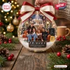 Front view of a clear spherical Christmas ornament featuring a fountain, a group on a sofa, and festive holiday decor.