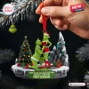 Hand holding a Grinch couple Christmas ornament featuring a personalized base on a snowy mountain and tree background.