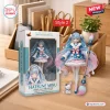 Front view of the Hatsune Miku 20th Anniversary Action Figure with its packaging box and a small rabbit figurine on a desk.