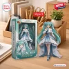 Front view of Hatsune Miku 20th Anniversary Action Figure beside its packaging box on a wooden desk.