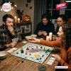 Horror Halloween 2026 Monopoly Game set on a wooden table with friends holding playing cards and festive candle decor.