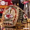 Closeup of a gold Kansas City Chiefs Championship ring featuring red accents, clear stones, and engraved championship years.