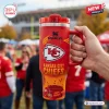 Hand holding a Kansas City Chiefs Red 40 Oz Stanley Tumbler outdoors in a stadium setting.