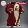 Kappa Alpha Psi Achievement Heritage T-Shirt in crimson and beige featuring fraternity shield and Greek lettering.