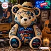 Front view of a plush bear wearing a straw hat featuring beach, palm tree, and musical tour designs.