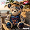 Front view of a plush bear wearing a straw hat with beach-themed graphics and musician imagery.