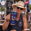 Man wearing a straw hat holds a Kenny Chesney Eric Church Vibe Room 2027 Stanley Tumbler in an outdoor setting.