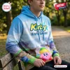 A person wearing a Kirby and the World Beyond Blue Sky Hoodie featuring a landscape print and a pink character graphic.