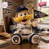 Front view of mascot plush pillow holding an NL Central Champions pennant and baseball on a wooden desk.
