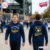 Man wearing a navy blue Milwaukee Brewers October Baseball 2026 hoodie showing front and back graphic designs.