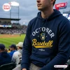 Man wearing a navy blue Milwaukee Brewers October Baseball 2026 hoodie at a stadium.