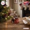 Close-up of a mischievous pitbull puppy looking into a red treat bag next to a lit Christmas tree.
