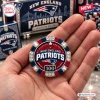 Close-up of a hand holding a New England Patriots poker chip with red, white, and blue accents and the number 100.