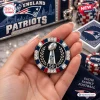 Closeup of a hand holding a decorative casino poker chip featuring a trophy graphic and New England Patriots branding.