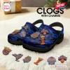 Side view of New York Knicks blue camo clogs with charms displayed on a fluffy white rug.