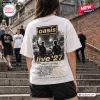 Back view of a person wearing a white t-shirt featuring a black and white concert graphic and Oasis band tour 2027 text.