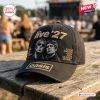 Side view of a black baseball cap featuring embroidered Oasis Live 27 text, band member imagery, and city names.