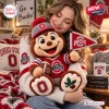 A woman hugging an Ohio State Buckeyes crochet mascot plush doll holding a small football and pennant flag.