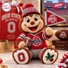 Front view of an Ohio State Buckeyes crochet mascot plush doll holding a small pennant and a football.