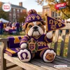 Front view of an Omega Psi Phi bulldog crochet plush toy holding a small pennant flag on a wooden bench.