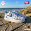 Side view of white custom Air Force 1 sneakers with blue diabetes awareness ribbons and dog graphics on a wooden boardwalk.