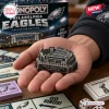 Close-up of a hand holding a small metal Lincoln Financial Field game token from a Philadelphia Eagles Monopoly game.