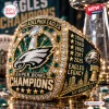 Close-up of a Philadelphia Eagles Super Bowl championship ring featuring green gems, team logo, and five star engravings.