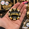 Close-up of a hand holding a black and gold Pittsburgh Steelers poker chip with a 100 denomination and crystal insets.
