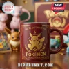 Pokemon 30th Anniversary Pikachu red coffee mug featuring gold laurel accents and Gotta Catch 'Em All text on a desk.