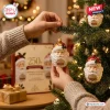 Santa Claus 250th Anniversary Advent Calendar glass ornament held by a hand near a decorated Christmas tree with lights.
