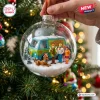 Hand holding a clear glass Christmas ornament containing a Mystery Machine van and character figures in a snowy scene.