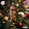 Snoop Dogg Hot Dog Christmas ornament with braids, sunglasses, and a gold chain hanging on a decorated pine tree branch.