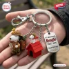 Hand holding a keychain with a scout beagle, red doghouse, and a 75th anniversary commemorative metal tag.