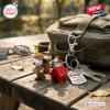 Close-up of a Snoopy Red Doghouse Beagle 75th Anniversary keychain attached to a backpack on a wooden table.