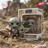 Front view of Grogu in Mandalorian armor vinyl figure beside its branded display box in a desert setting.