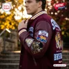 Side view of a person wearing a maroon varsity jacket featuring embroidered patches and text.